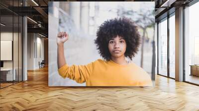 one serious young african or american woman with her arm up with close hand looking at camera. Black Lives Matter concept Wall mural