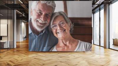 Portrait of couple of two happy and healthy seniors old people smiling and looking at the camera. Close up of mature grandparents enjoying and having fun together at home indoor.. Wall mural