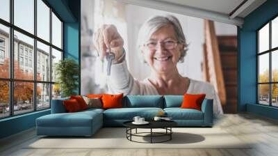 Portrait of happy senior woman holding keys of new home or property. Old lady showing or giving keys to house. Elderly female happy for moving into new apartment Wall mural