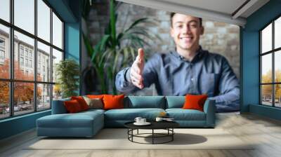 Portrait of happy young male hr stretching hand inviting you spectator to join corporate team, friendly capable manager looking at camera extending hand for handshake welcoming new client or colleague Wall mural