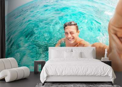 Portrait of happy young man taking a selfie of him in the beach in a blue turquoise water having fun and enjoying alone vacations outdoors. Wall mural