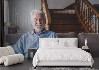 Portrait of old man smiling and looking at the camera sitting on the sofa from home. Closeup male person senior cheerful indoor.. Wall mural