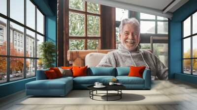 Portrait of old man smiling and looking at the camera sitting on the sofa from home. Closeup male person senior cheerful indoor.. Wall mural