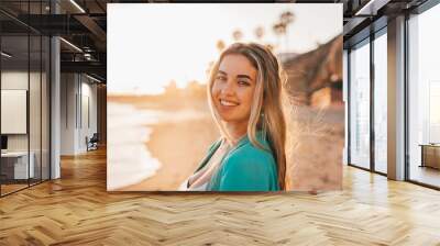 Portrait of one happy beautiful woman on the sand of the beach enjoying and having fun at the sunset of the day. Looking at the camera smiling.. Wall mural