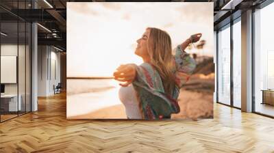 Portrait of one young woman at the beach with openened arms enjoying free time and freedom outdoors. Having fun relaxing and living happy moments.. Wall mural