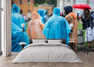 People in the rain with accumulated umbrellas in tourist zone or waiting line. Wall mural