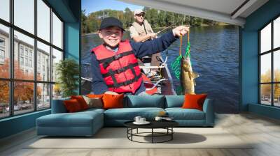 Smiling boy fisherman in a canoe holds up a stringer with nice walleyes Wall mural