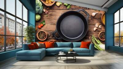 Various organic vegetables ingredients and empty iron cooking pot, wooden bowls, spoons on wooden background. Top view, copy space. Organic vegetables ingredients for vegan cooking. Clean eating food Wall mural