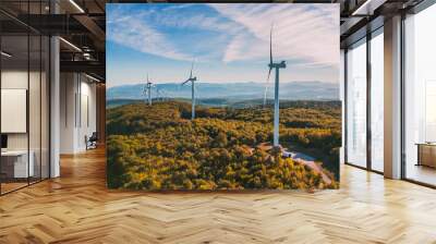 View of a wind farm in a mountainous forest field with mountains in the background. View during the rising sun. Sunrise. Wall mural