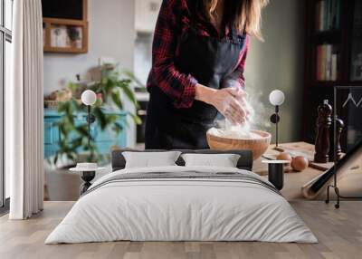 Woman cooking pastries and bread at home looking for recipes on tablet Wall mural