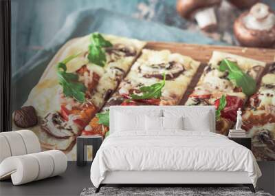 Freshly baked flammkuchen, traditional french tarte flambee or german pizza in a vegetarian recipe with mushrooms, cream cheese, tomatoes and arugula, on  light greenwooden board and table Wall mural