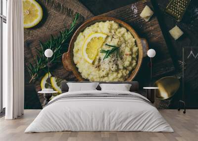 Lemon rice risotto with rosemary and fresh lemon slices on dark wooden background, top view Wall mural