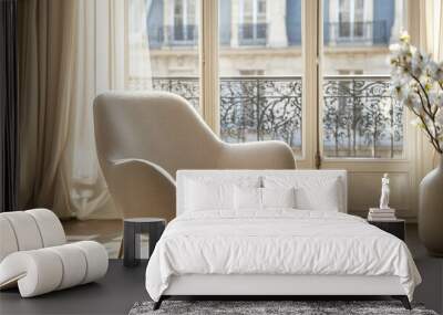 A modern and comfortable armchair in a light beige color against a bright window with a blurred Paris view Wall mural