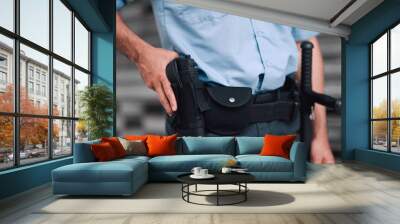 Hand, gun and security with an officer on duty or patrol in the city for safety and law enforcement. Police, service and armed response with a guard outdoor in an urban town for crime prevention Wall mural