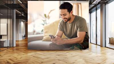 Happy, man and texting on cellphone in living room for online mobile app, scroll social media and notification on sofa. Asian male person typing on smartphone, contact and internet download at home Wall mural