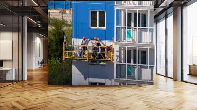 construction workers installers high-rise workers industrial climbers, painters on the lift paint the facade of the building, completion of construction of a residential building or office Wall mural