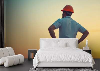 A builder in a helmet stands with his back and looks into the distance. Construction industry. Head of the section. General contractor Wall mural