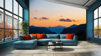 Colorful dawn landscape with beautiful mountains silhouettes and golden gradient sky with lilac clouds. Vivid mountain scenery with picturesque multicolor sunset. Scenic sunrise view to mountain range Wall mural