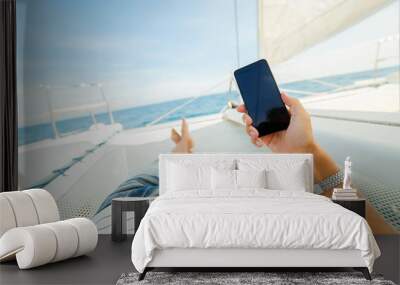 Phone in the hand of a vacationer on a yacht Wall mural