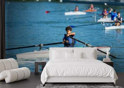 Boy training rowing in a lake near his home with his classmates Wall mural