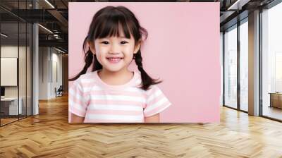 Asian smiling little girl portrait isolated on light pink background. Wall mural