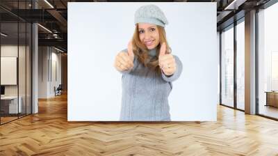 Beautiful young woman wearing casual winter sweater standing over isolated background approving doing positive gesture with hand, thumbs up smiling and happy for success. Winner gesture. Wall mural