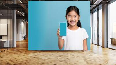 Happy kid tween teen asian girl holding phone smartphone mock up showing white blank display for advertising Wall mural