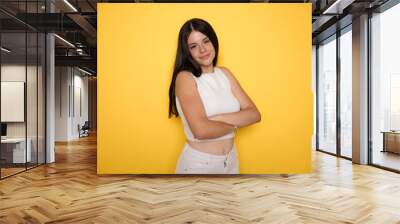 Happy teenager, positive and smiling emotions of teen girl. Portrait of caucasian teen girl with arms folded, isolated on yellow background. Cute teenager child. Wall mural