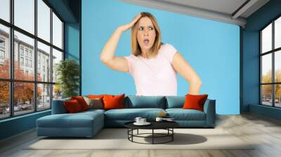 Image of shocked excited young lady standing isolated over blue background. Wall mural