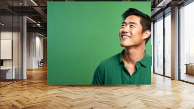 Side view of attractive adult Asian man smile isolated on green background. Wall mural