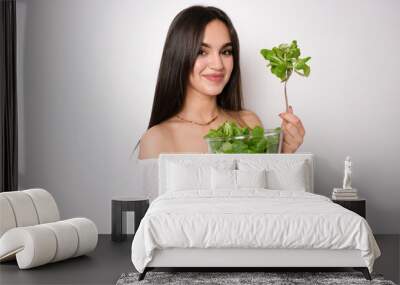 Young caucasian woman isolated on white background holding a bowl of salad with happy expression Wall mural