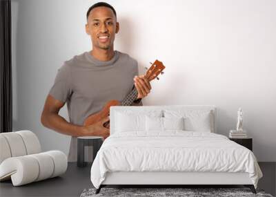 Young handsome african american man plays ukulele isolate over white background, Wall mural