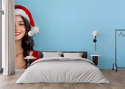 Young woman portrait in Christmas style dress with Santa hat isolated on blue background. Wall mural