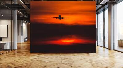 Air plane taking off at sunset near to the sun with beautiful red cloud in background Wall mural