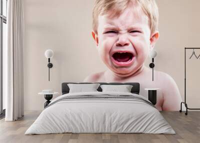 Portrait of Stormily Weeping Caucasian Blond Boy Against Beige Background. Wall mural