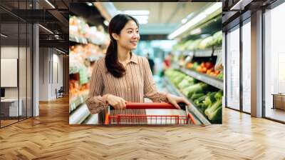 asian woman doing grocery shopping. asian women shopper picking up vegetables in the supermarket Wall mural