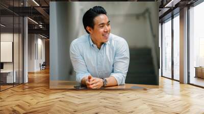 A candid portrait of a smiling middle-aged Japanese man in a light blue long-sleeved polo. He has short hair and looks very happy. Wall mural