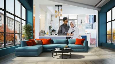 A young Muslim Malay couple sit at a table top counter and enjoy a coffee early in the morning when they break fast.  Wall mural