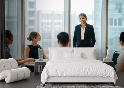 An Asian Indian businesswoman is having a conversation with her colleagues in a conference room and looking forward for their project. She's wearing a black blazer and white blouse with a black skirt. Wall mural