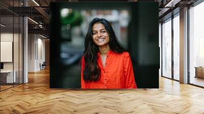 Portrait of attractive and young Indian woman smiling in an orange ethnic dress during the day Wall mural