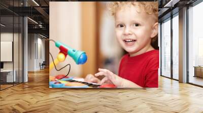 Adorable little boy playing with a toy microphone Wall mural