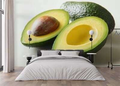 Close-up of cut avocado, pit visible, arranged on clean white surface Wall mural