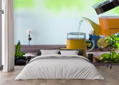 Mint tea. Mint and lemon tea pouring into glass cup on wooden table. Natural and healthy tea concept Wall mural