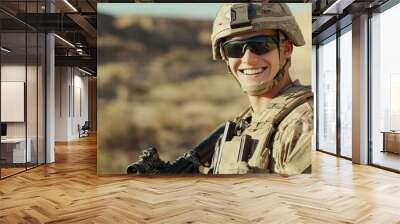 A young male soldier in desert combat gear smiles confidently during a military operation in a desert environment, holding a rifle. Wall mural