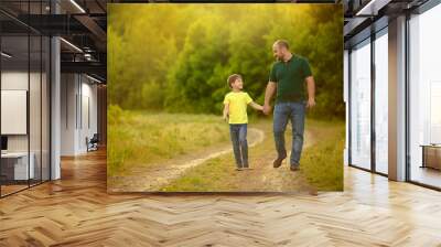 A happy family. father and son walk along the road and hold hands for a walk in the forest. Wall mural