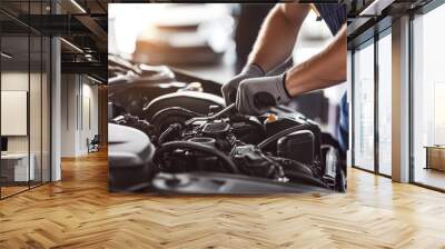 Close up of mechanic hands working on a car engine in a garage against a white background. The man is using a wrench to repair and fix the vehicle in the shop with the hood open Wall mural