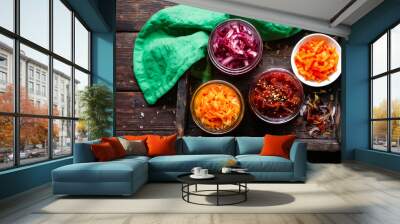 Assorted pickled vegetables in jars on rustic wood, top view Wall mural