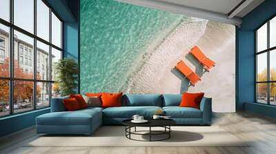 two orange sun loungers on the seashore with turquoise transparent clear water on a sunny day. diagonal composition with copy space Wall mural