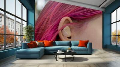 Teenage girl with ombre colored pink hair with wireless earbuds earphones in her hand. Music phone calls podcast audiobooks listening Wall mural