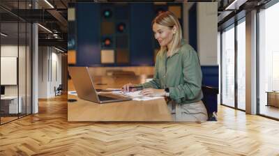 Smiling woman entrepreneur working on laptop in modern coworking. Distance work concept Wall mural